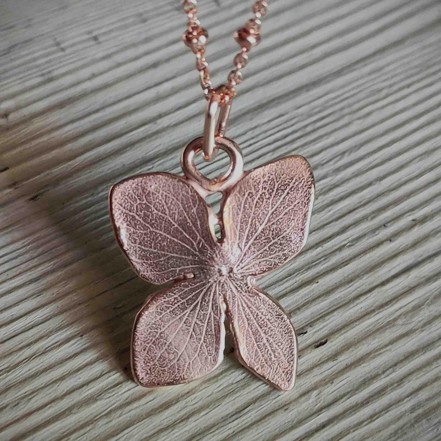 Collar de mariposa en rosa dorado, hecho de metal con detalles detallados, elegante y delicado.