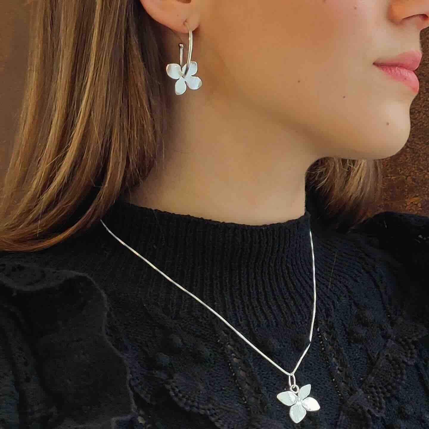Pendientes y collar de plata con diseño de flor, ideal para un look elegante y romántico.