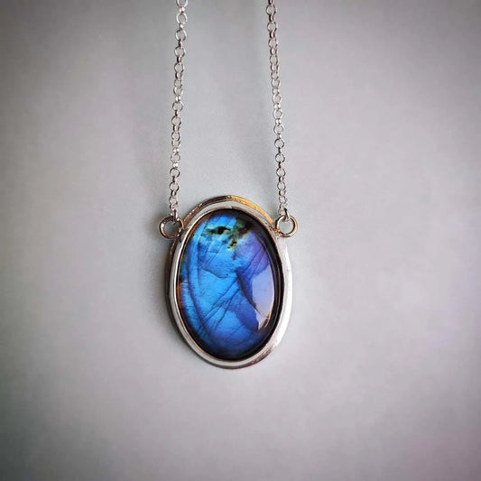 Collar de plata con pendant ovalado de labradorita azul y dorado, estilo moderno y elegante.