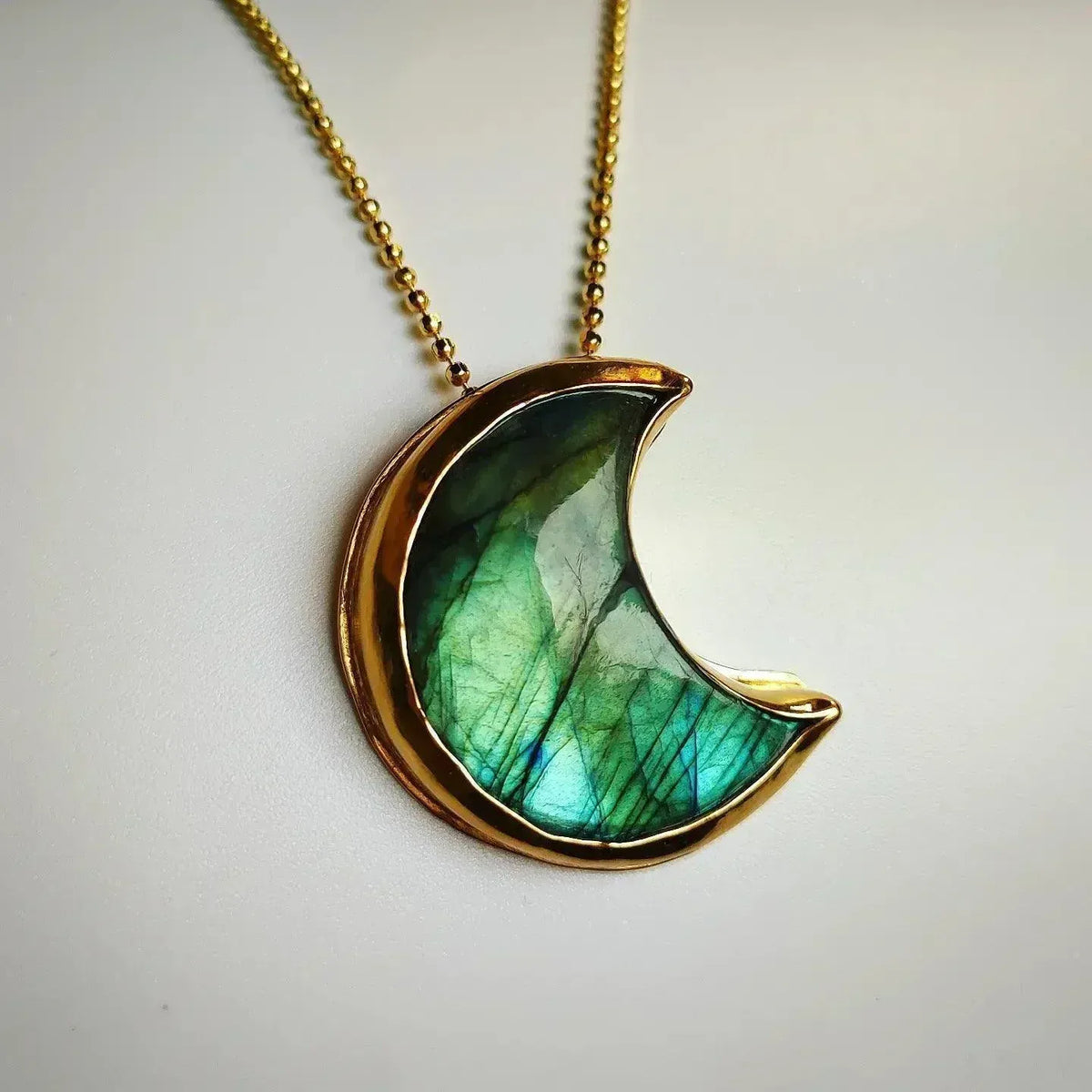 Collar con colgante de luna en labradorita verde y dorado, estilo bohemio y elegante.