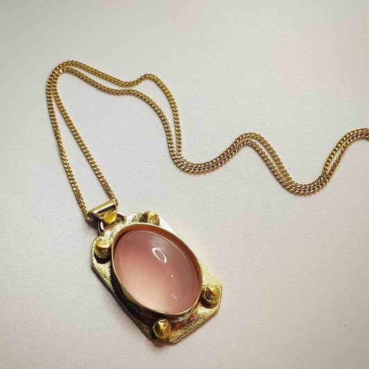 Collar dorado con colgante ovalado rosa de vidrio, elegante y moderno, ideal para ocasiones formales.
