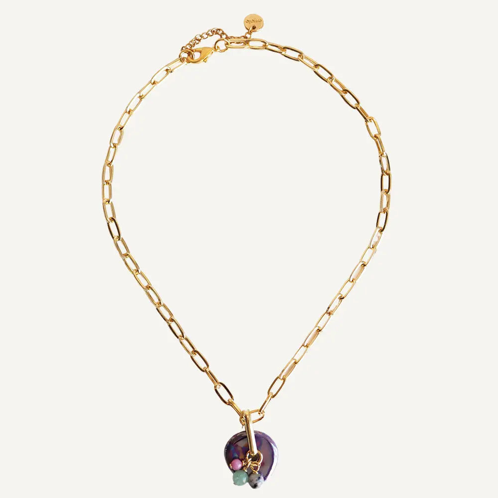 Collar dorado con eslabones grandes y colgante de concha morada y piedras en tonos verdes.