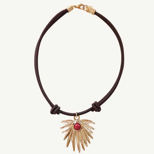 Collar de cuero marrón con colgante dorado en forma de ala y piedra roja, estilo bohemio.