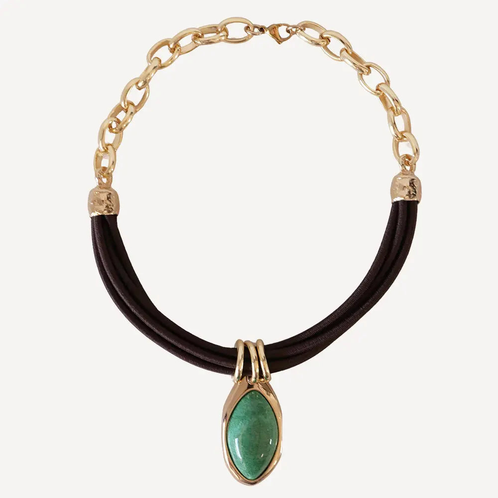 Collar de cadena dorada con piedra verde y cordón negro, estilo elegante y moderno.