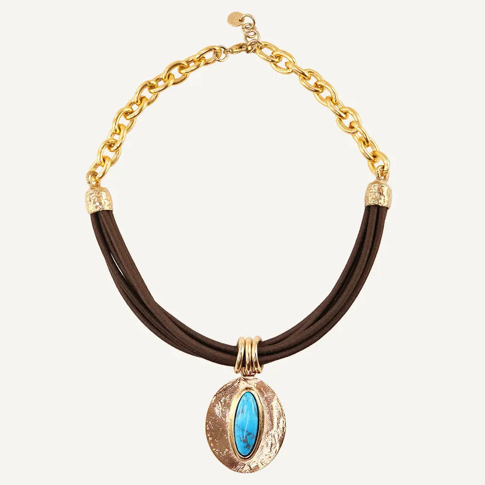 Collar de cadenas doradas con cuero marrón y piedra turquesa central, estilo bohemio y elegante.