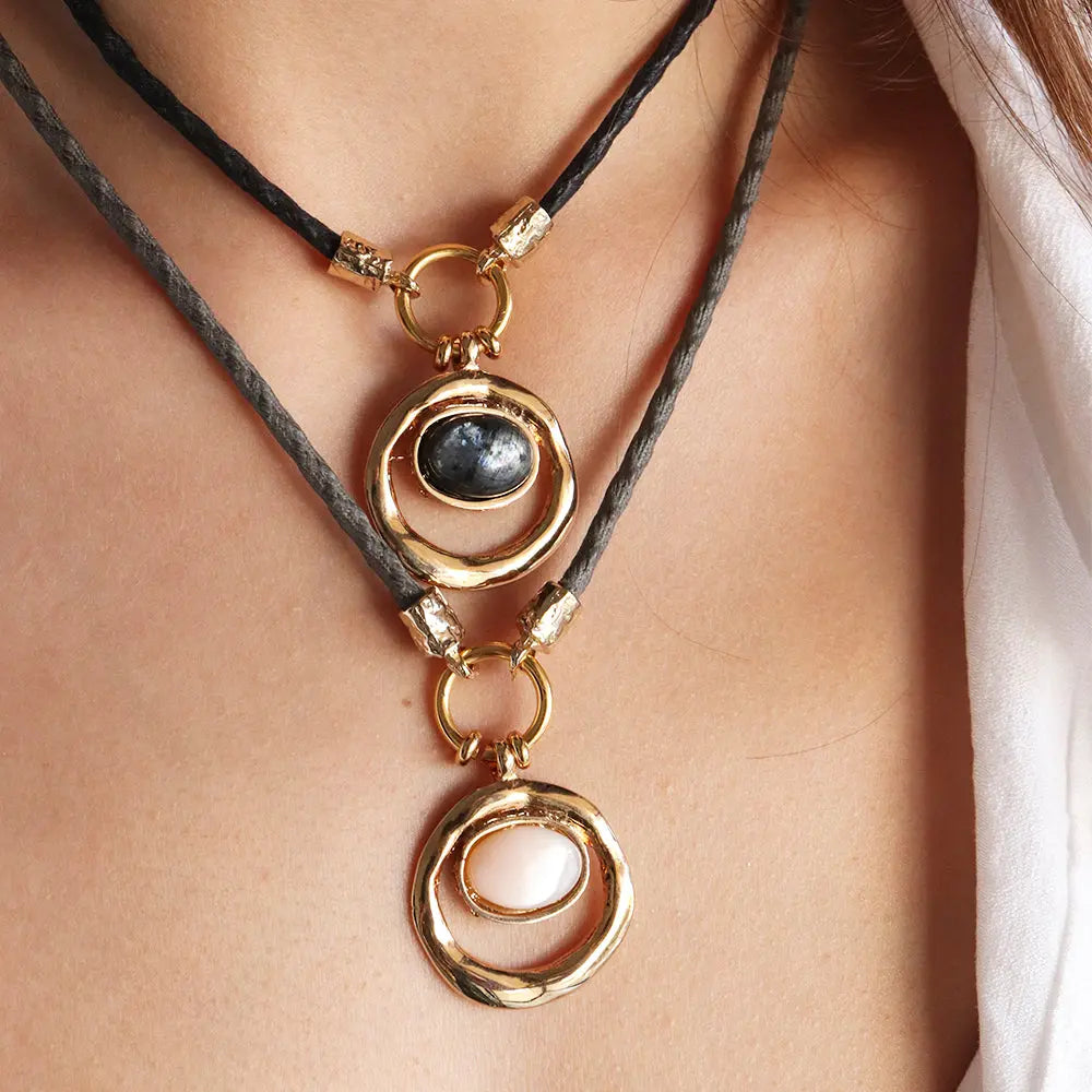 Collar de doble cadena en tonos negro y gris, con esferas doradas y piedras de ónix y rosa. Estilo elegante y moderno.