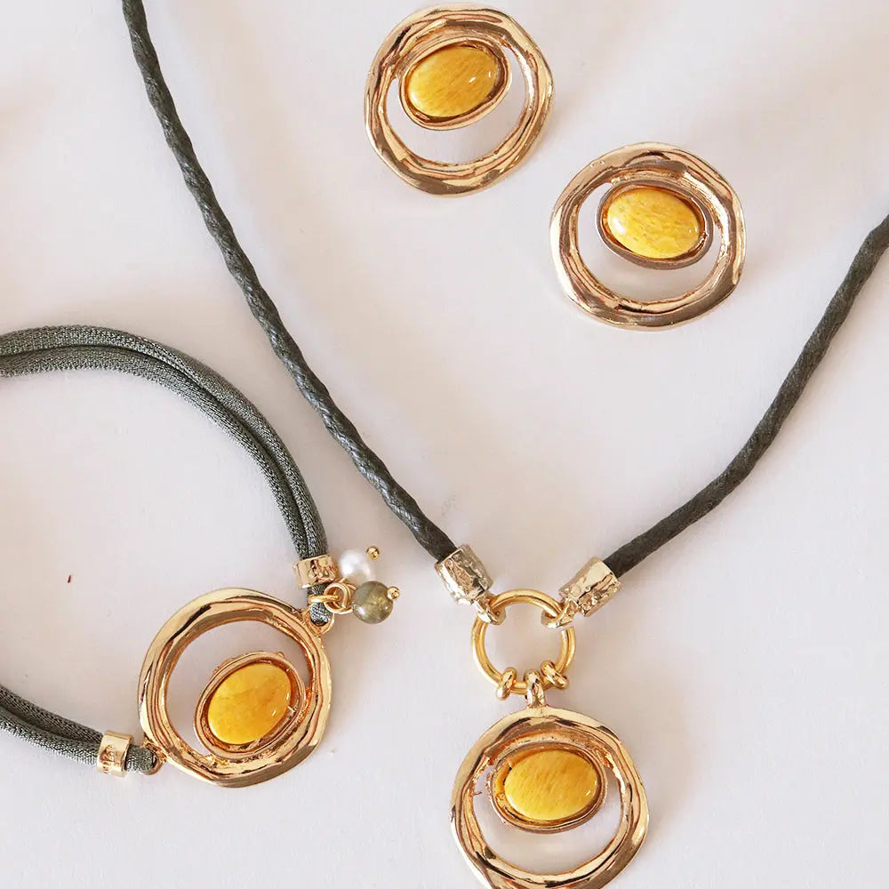 Conjunto de joyas de oro y amarillo, incluye pulsera y aretes, con detalles en cuerda gris y diseño moderno.
