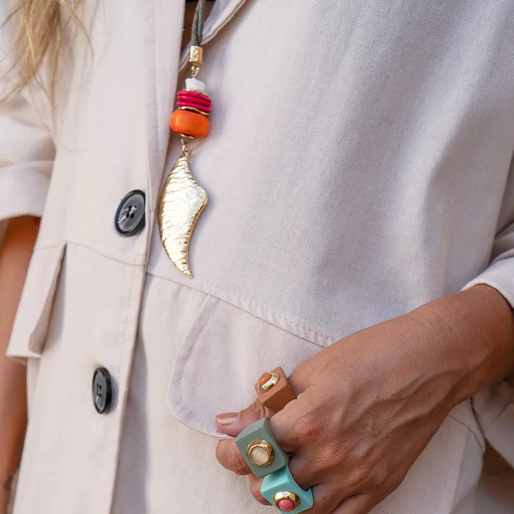 Collar dorado con cuentas de colores y anillos de cuero en tonos nude y verde. Look moderno y elegante.