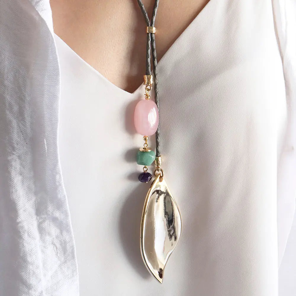 Collar largo bohemio con piezas de resina rosa y verde, y colgante dorado en forma de hoja.
