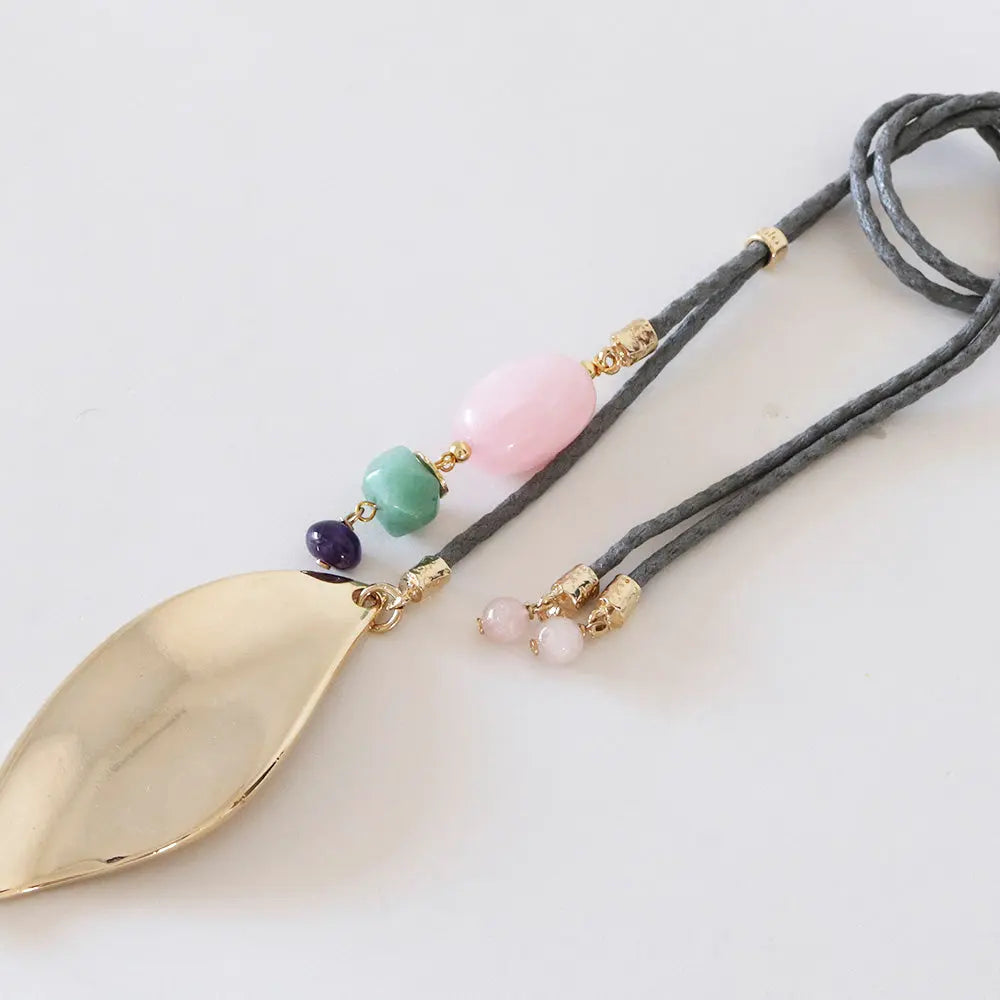 Collar de acero dorado con hoja, cuentas de jade verde, cuarzo rosa y cordón gris. Estilo bohemio y elegante.