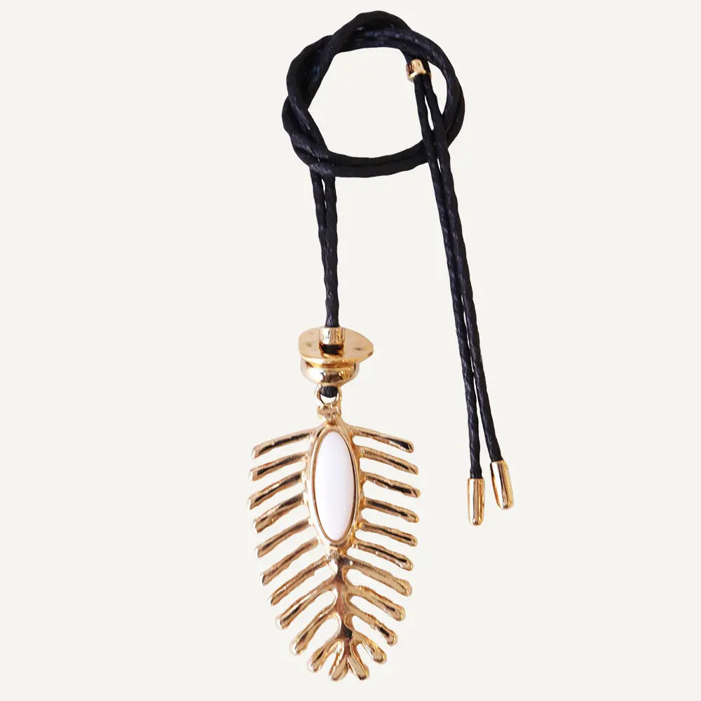 Collar bohemio de metal dorado con diseño de hoja y cordón negro, cuenta blanca en el centro.
