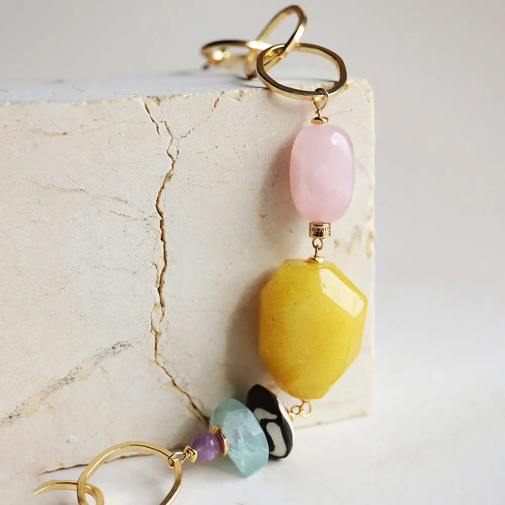 Pendientes largos en oro con piedras amarillas, rosas y verdes, estilo bohemio y moderno.