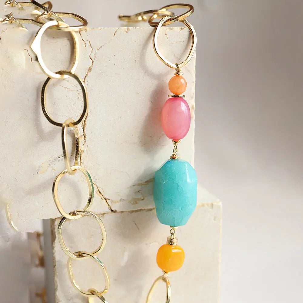 Collar de eslabones dorados con piedras turquesas, rosas y naranjas, estilo moderno y vibrante.