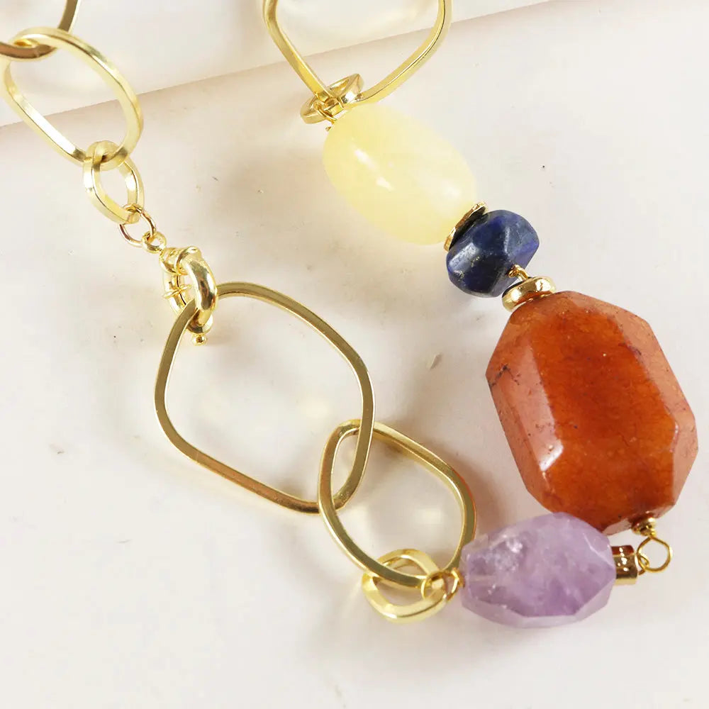 Pendientes de metal dorado con gemas coloridas: ámbar, sodalita, cuarzo rosa y amatista; estilo moderno y elegante.