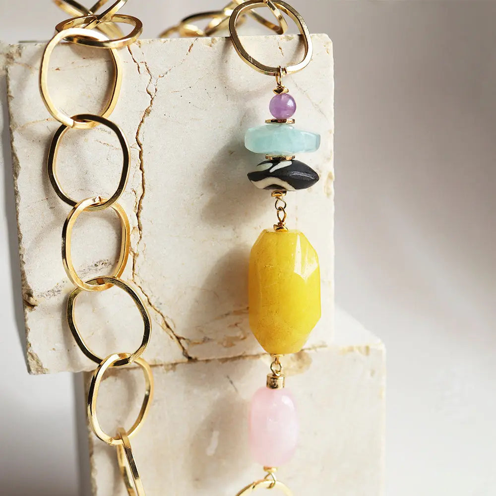 Collar de eslabones dorados con cuentas de ónix, amatista, aguamarina y piedra amarilla. Estilo elegante y moderno.