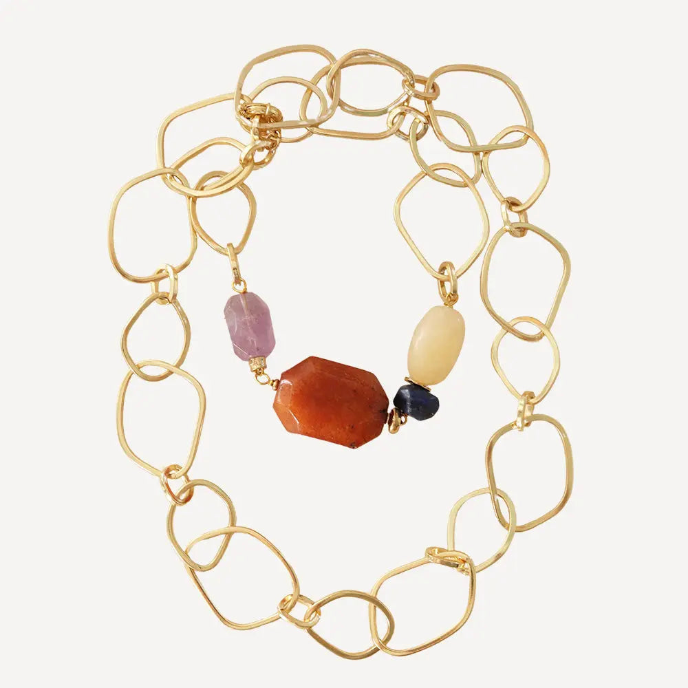 Collar dorado de eslabones con piedras preciosas en tonos naranja, púrpura y amarillo. Estilo elegante y moderno.