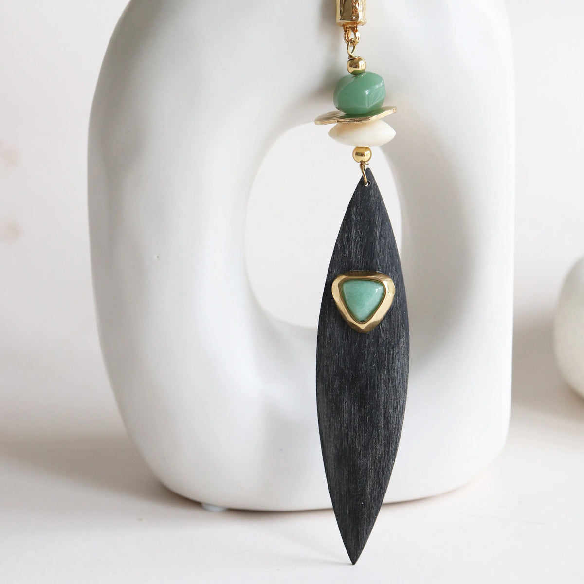 Pendientes de madera negra con detalle dorado y cuentas verdes, estilo moderno y elegante.