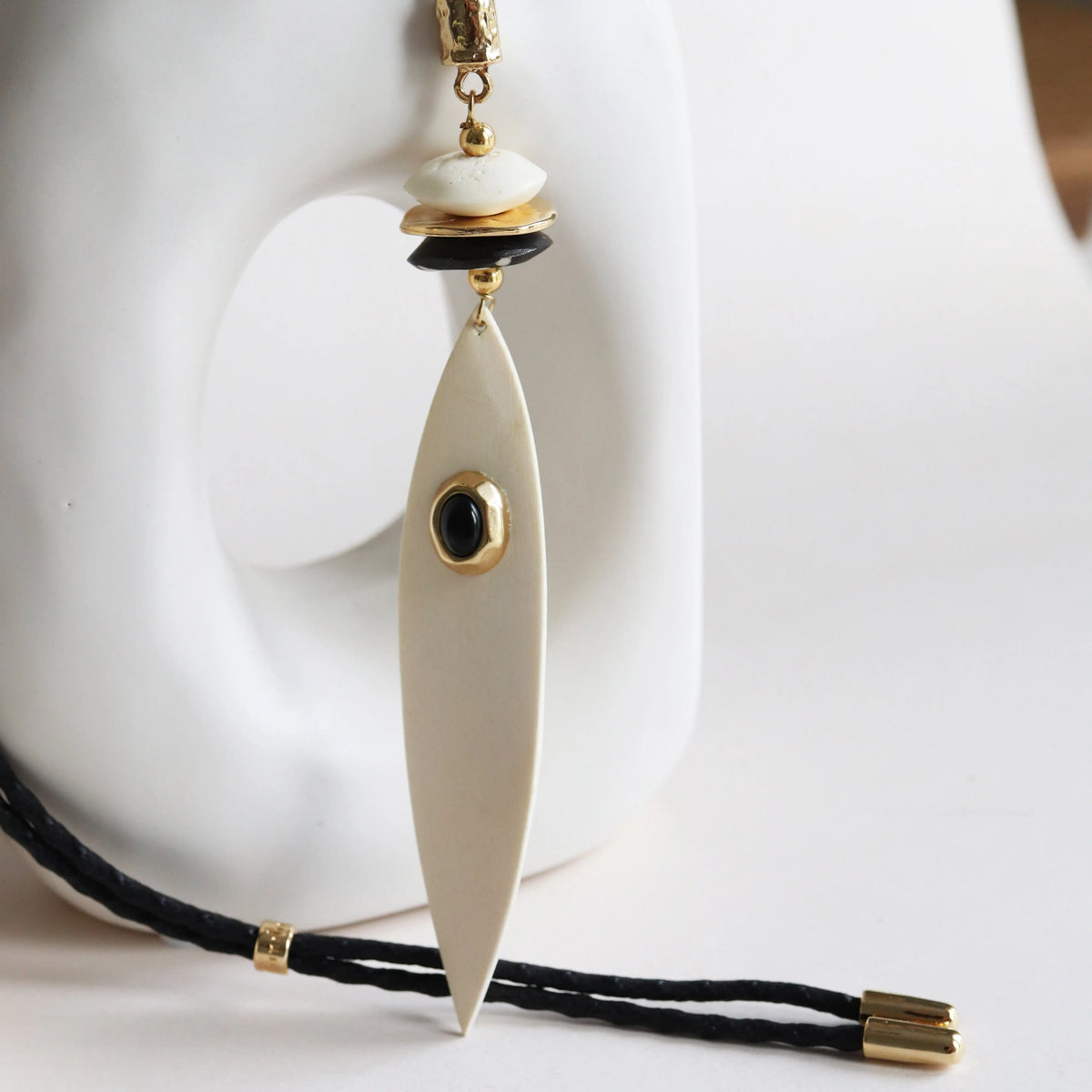 Collar largo de resina en tonos blancos y negros con detalles dorados y diseño elegante.