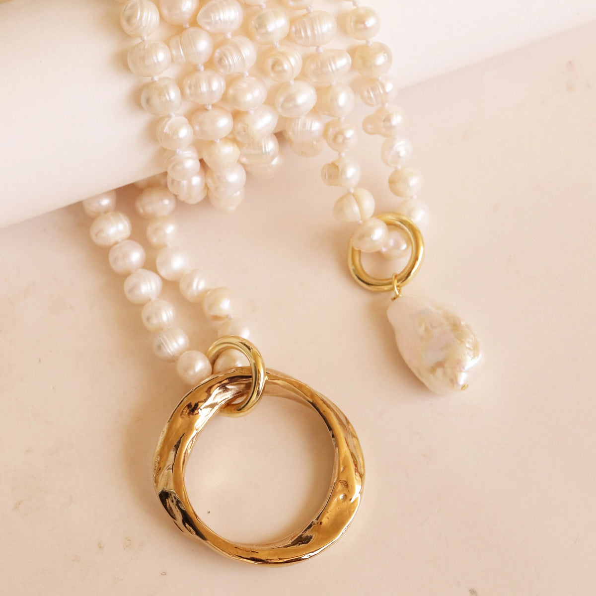 Collar de perlas blancas con anillo dorado y colgante de perla única, estilo elegante y moderno.