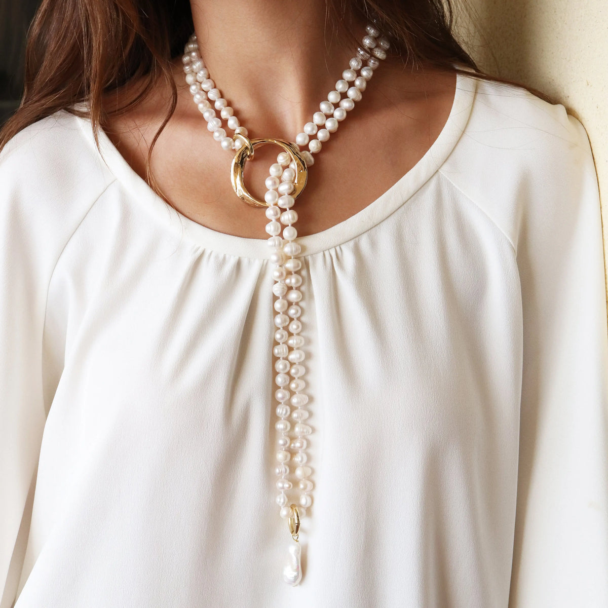 Collar de perlas blancas con aros dorados y detalle en perla, estilo elegante y contemporáneo.