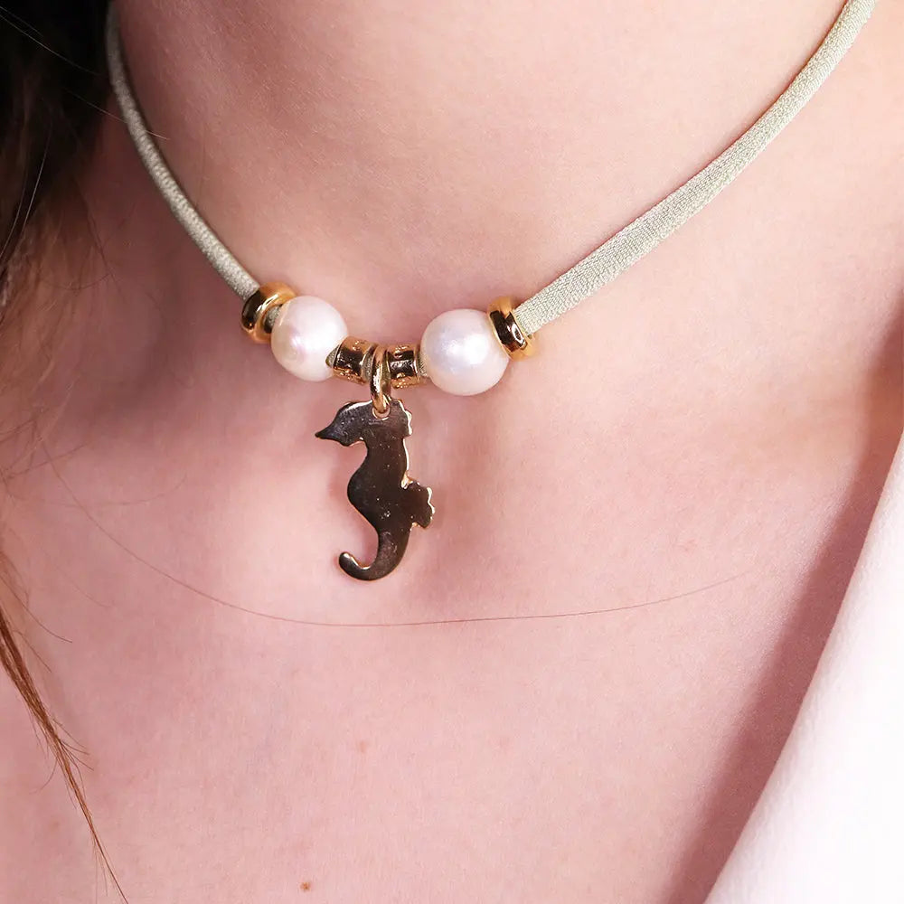 Collar de terciopelo verde claro con charm de caballito de mar y perlas blancas, estilo elegante y moderno.