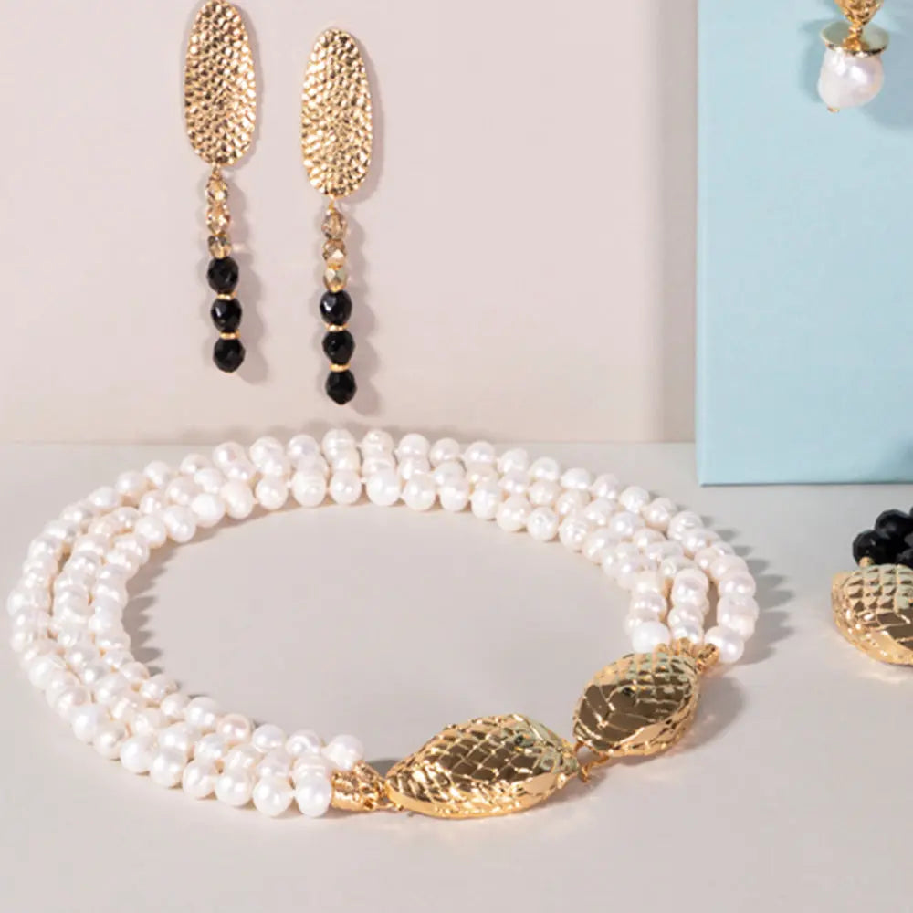 Collar de perlas blancas con detalles dorados y pendientes largos de oro, elegante y sofisticado.