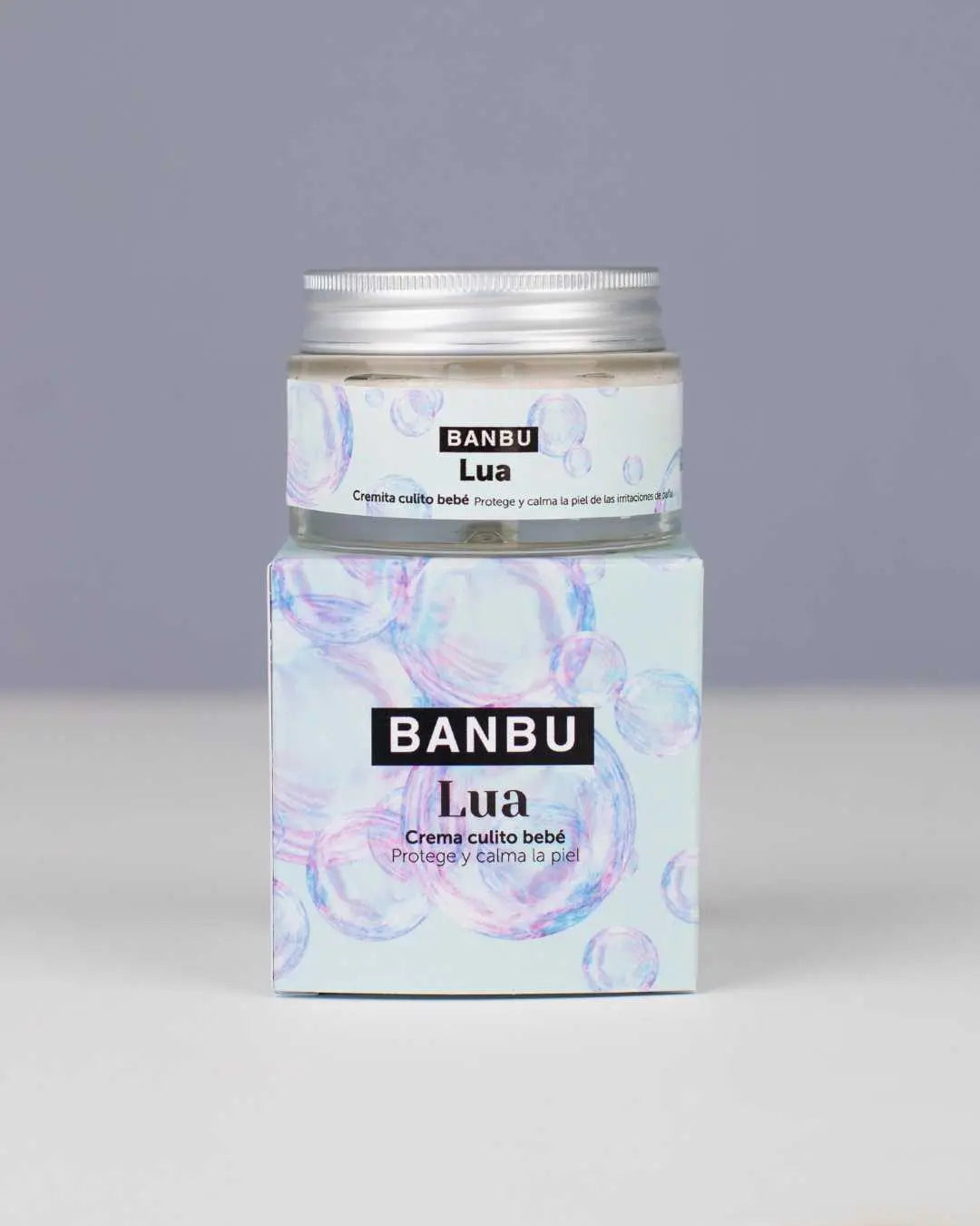 Tarro de crema LUA de Banbu sobre su caja de cartón azul claro con burbujas, diseño ecológico sobre fondo gris.