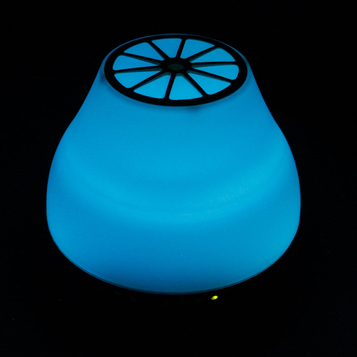 Difusor de aroma Ancient Wisdom, forma cónica, iluminado en azul intenso con tapa superior de diseño radial.