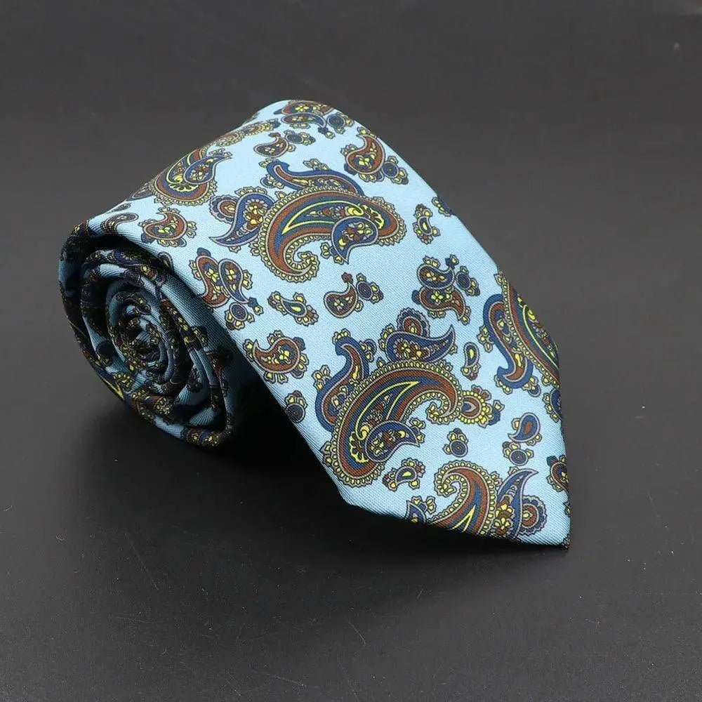 Corbata de tela azul claro con estampado paisley en tonos mostaza, azul oscuro y burdeos sobre fondo liso.