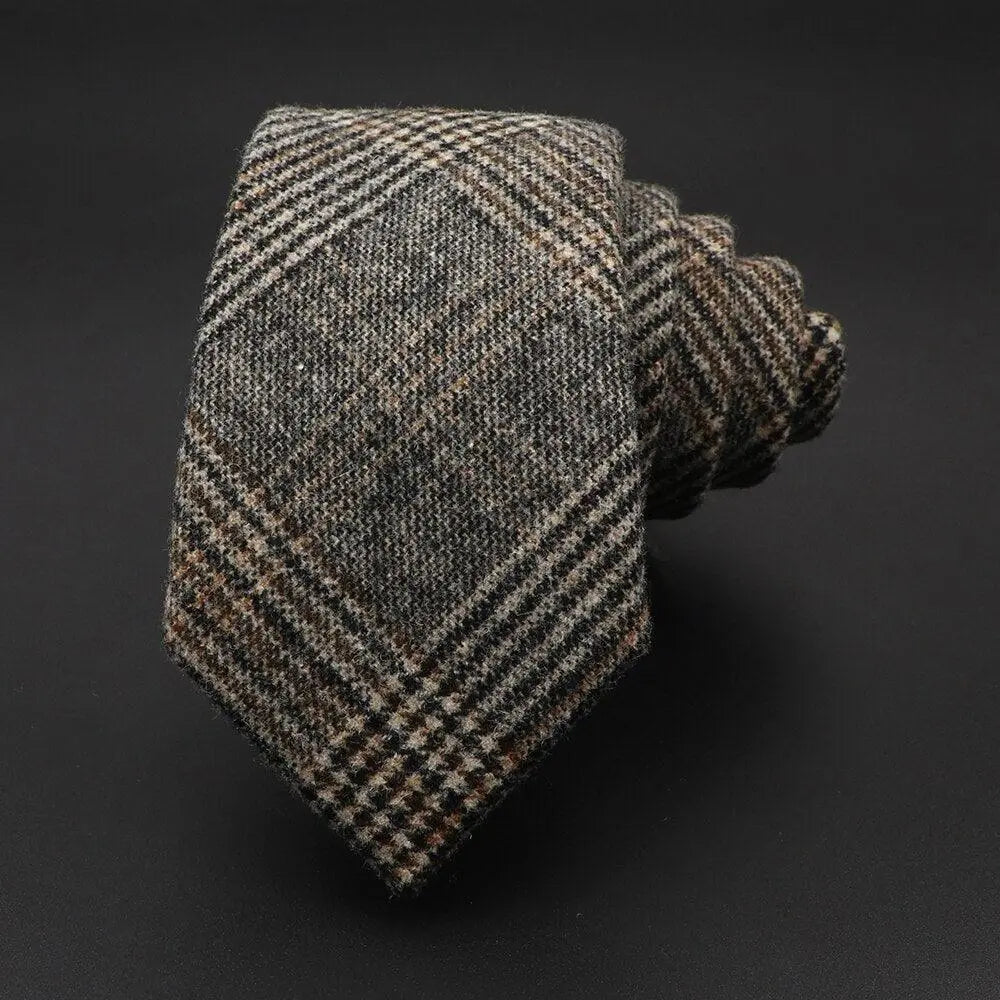 Corbata de lana enrollada con estampado de cuadros en tonos marrón y gris, textura rústica y estilo clásico.