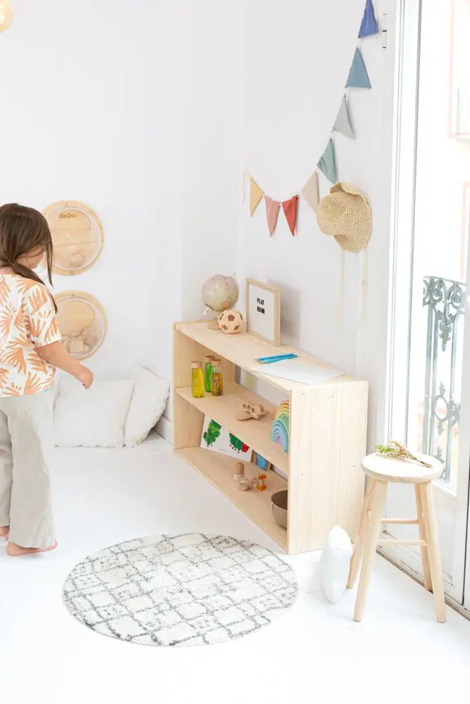 Estantería de madera clara con estantes abiertos, decorada con objetos coloridos, ideal para habitaciones infantiles.