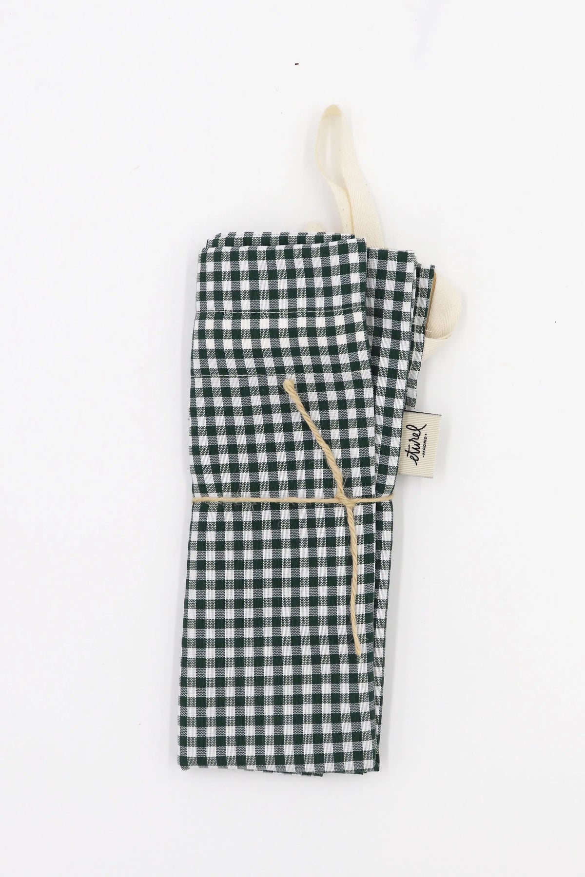 Panera de tela con estampado de cuadros vichy en verde y blanco, plegada y atada con un cordel sobre fondo blanco.