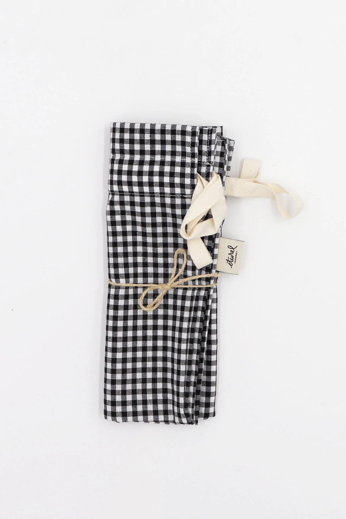 Rectangular bread bag in black and white gingham fabric, tied with a beige ribbon and twine, isolated on white.