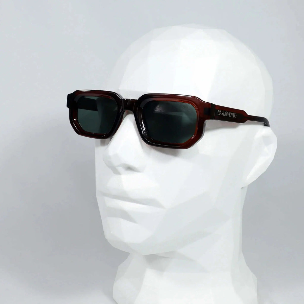 Gafas de sol rectangulares color rojo oscuro con montura de acetato y cristales oscuros sobre maniquí blanco.