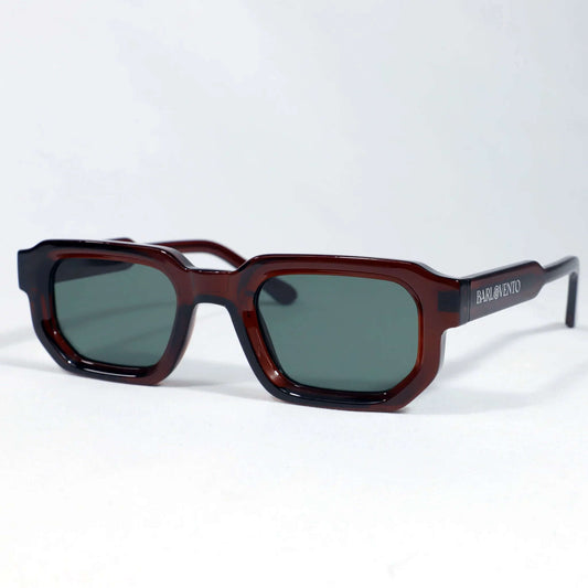 Gafas de sol de montura rectangular color rojo oscuro traslúcido y lentes oscuras de tono verdoso.