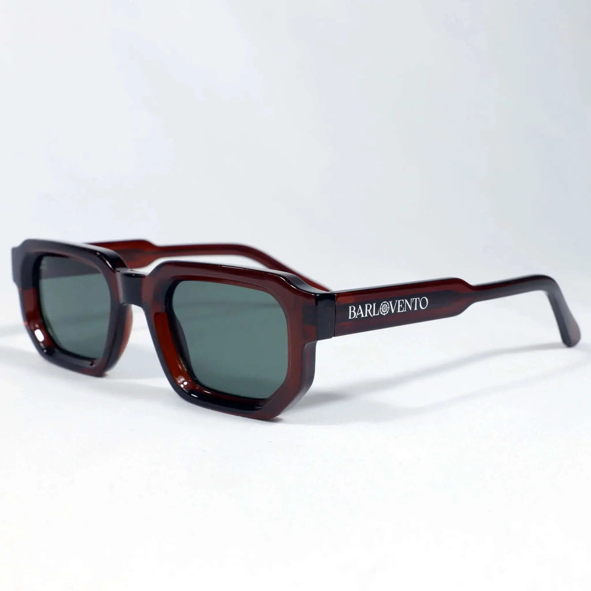 Gafas de sol de montura geométrica color rojo sangre brillante y lentes oscuras de tono verde.