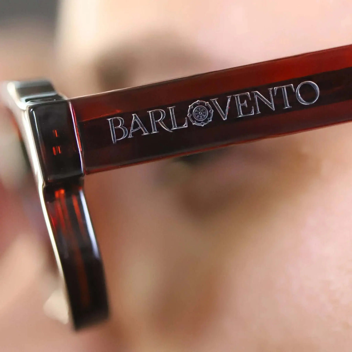 Gafas de sol de pasta color rojo sangre con acabado translúcido, enfoque en la patilla y bisagra metálica.