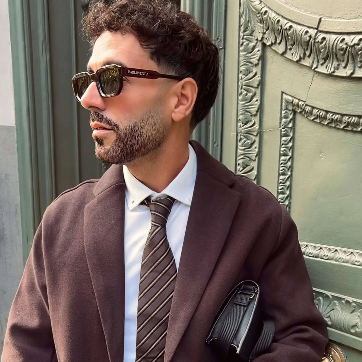 Gafas de sol de montura rectangular color rojo oscuro y lentes verdes, estilo clásico y elegante sobre un hombre.