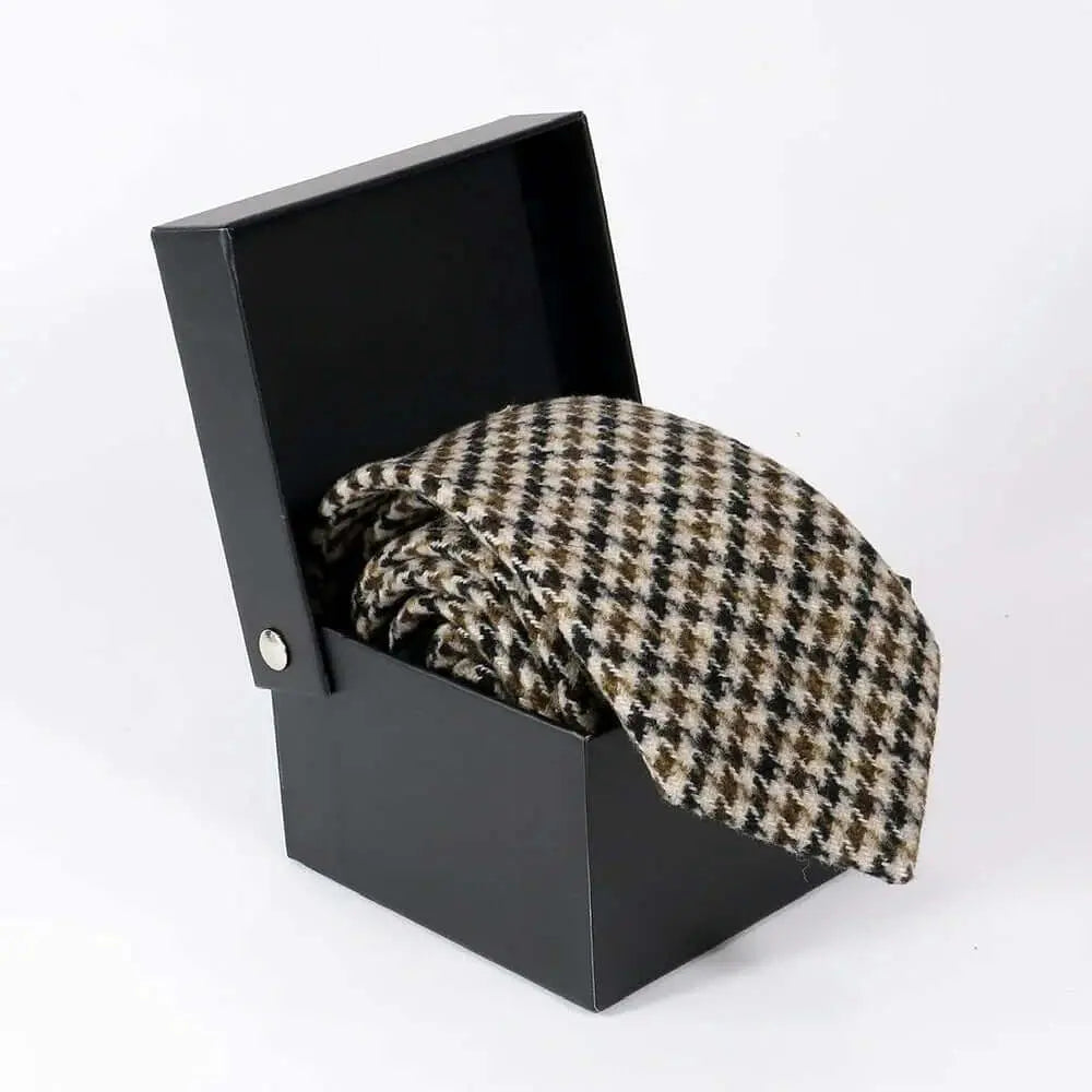 Corbata de lana con patrón de pata de gallo en tonos marrón, negro y crema, presentada en una caja negra abierta.