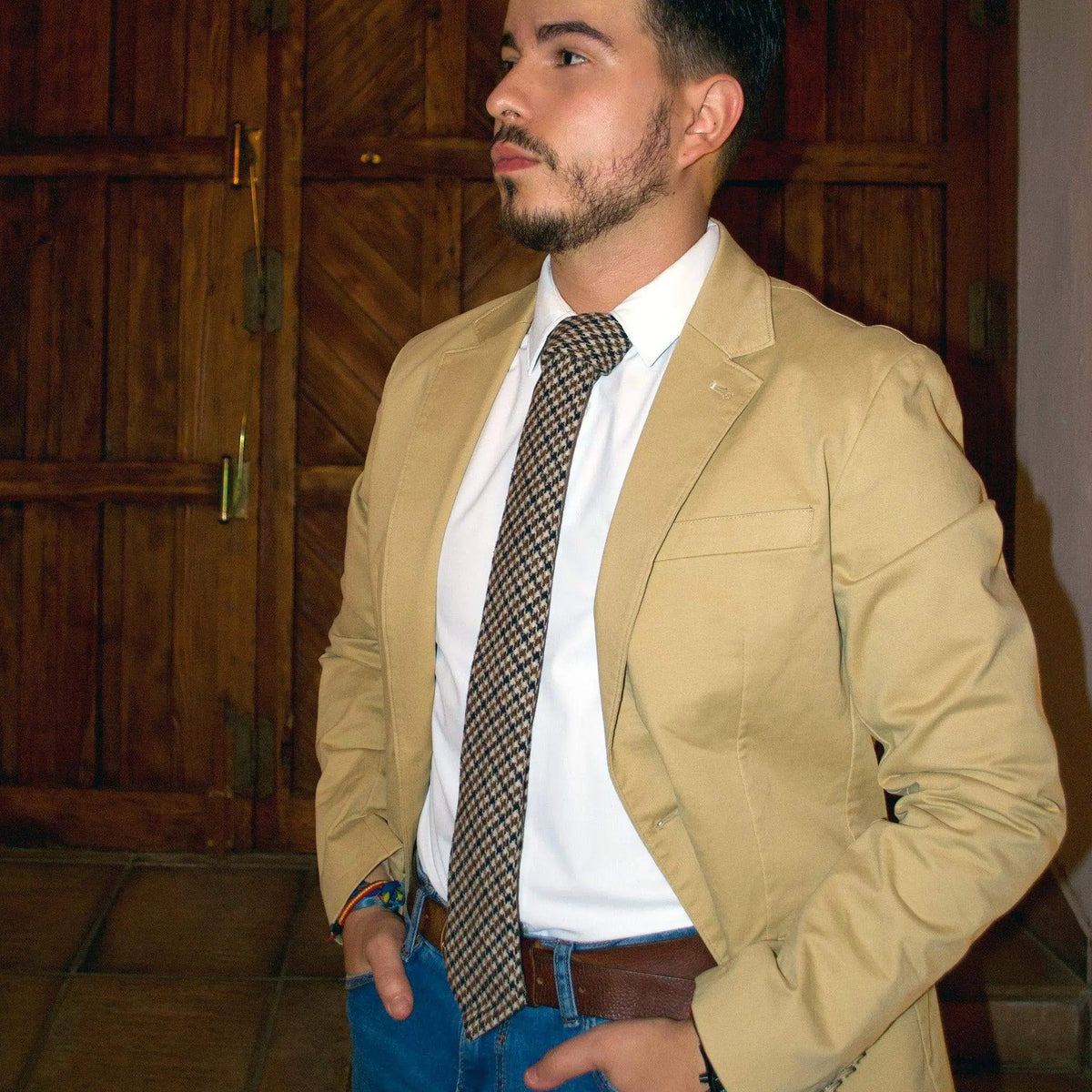 Corbata de lana con patrón de pata de gallo en tonos marrones, estilo clásico y elegante sobre camisa blanca.