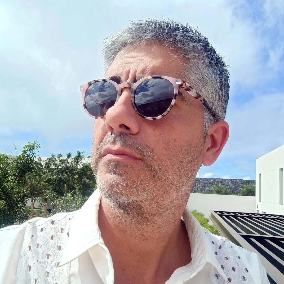 Hombre con gafas de sol redondas de acrílico con patrón de carey beige y marrón, estilo casual en exterior.