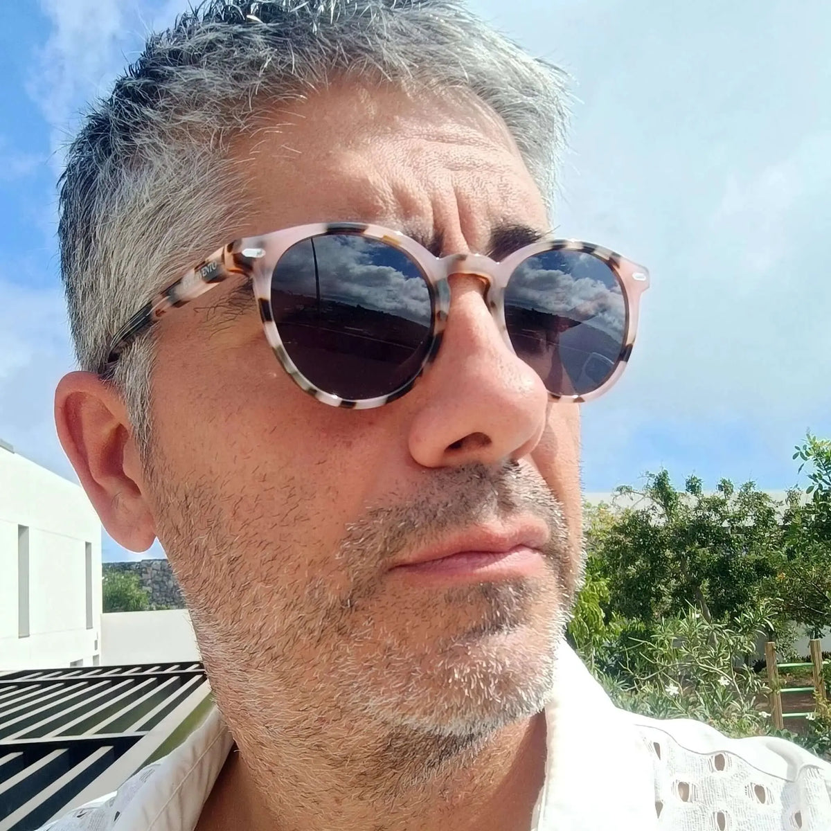 Hombre con gafas de sol redondas de acrílico con estampado de carey claro en exterior soleado.