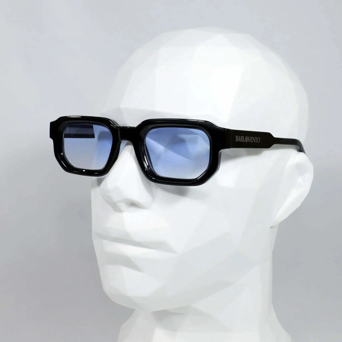 Gafas de sol rectangulares con montura negra brillante y cristales degradados en azul, sobre un maniquí blanco.