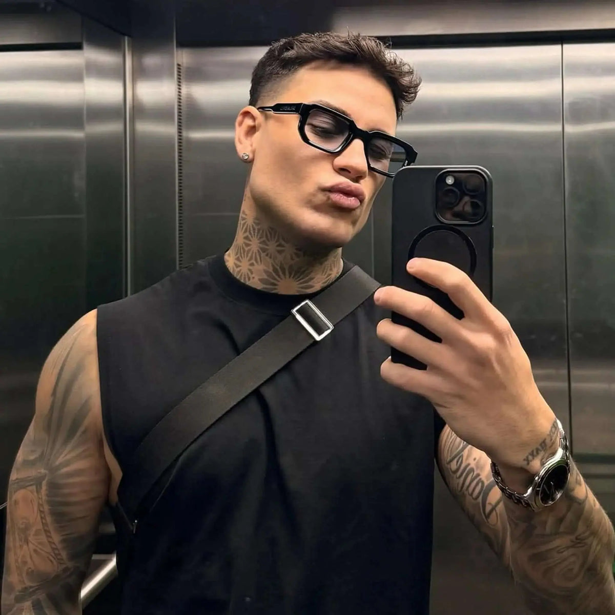 Gafas de sol negras de estilo rectangular con montura gruesa y lentes en tono azulado, ideales para un look urbano.
