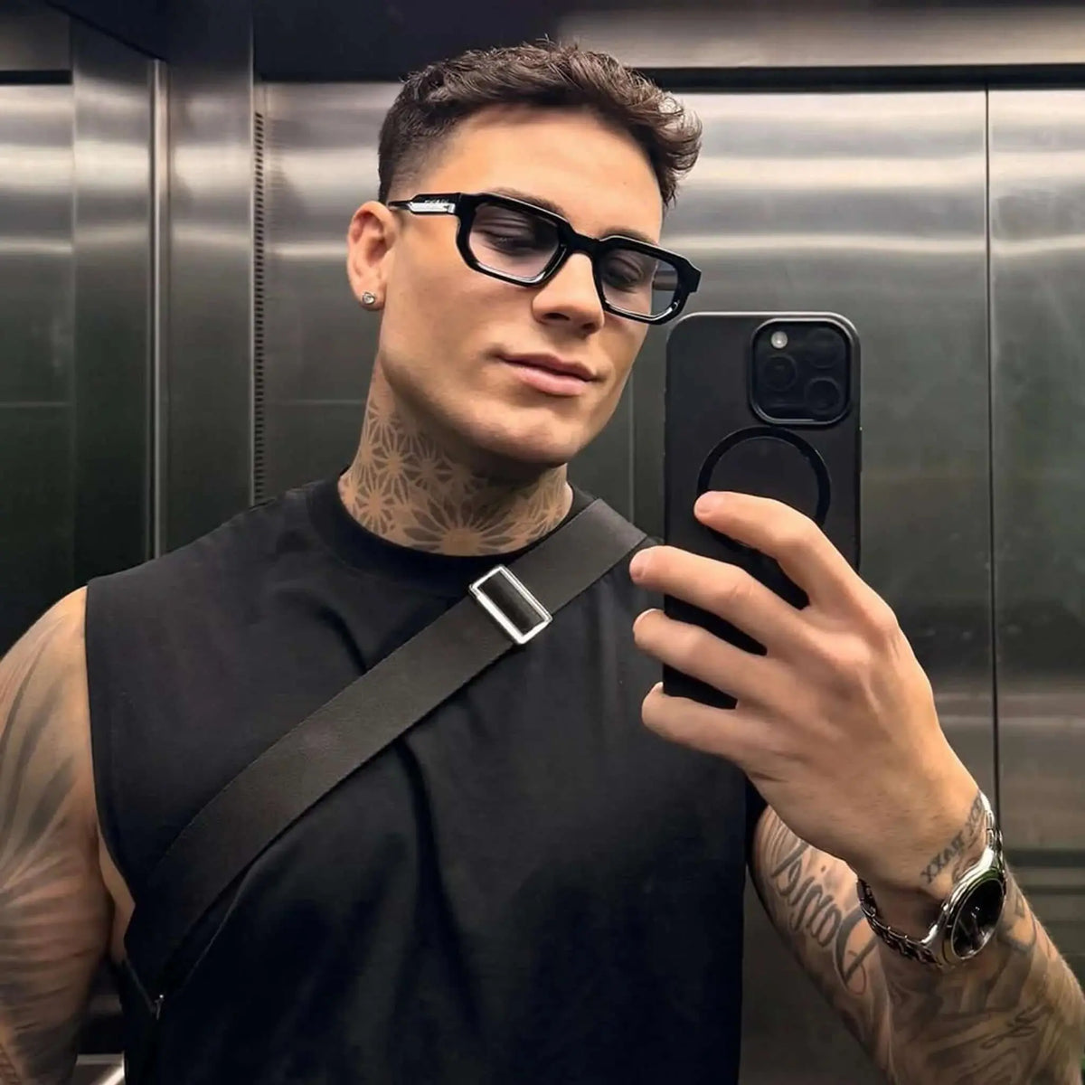Gafas de sol rectangulares con montura negra gruesa y lentes azuladas, estilo moderno y urbano.