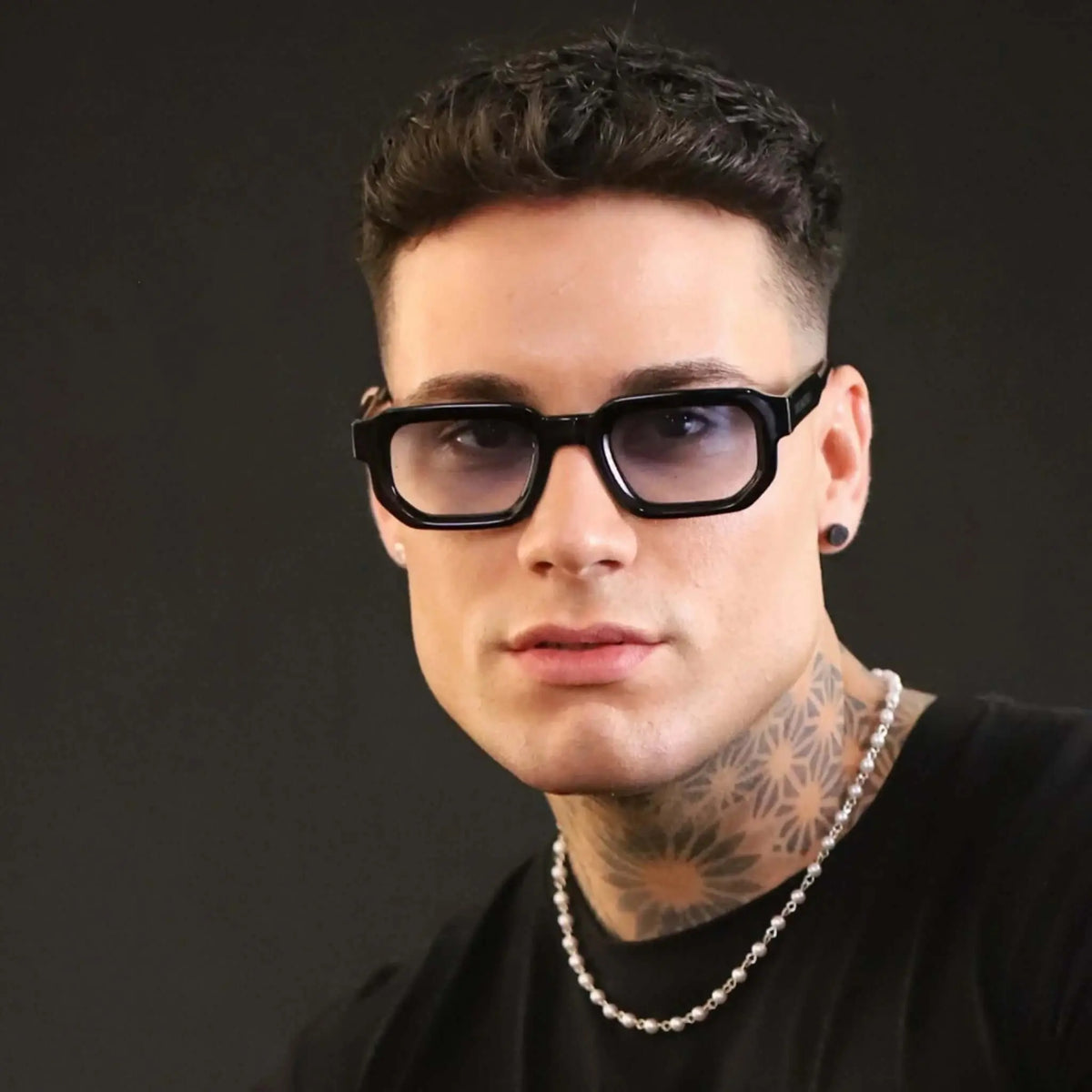 Gafas de sol de montura negra rectangular y lentes con un ligero matiz azul, estilo moderno y elegante.