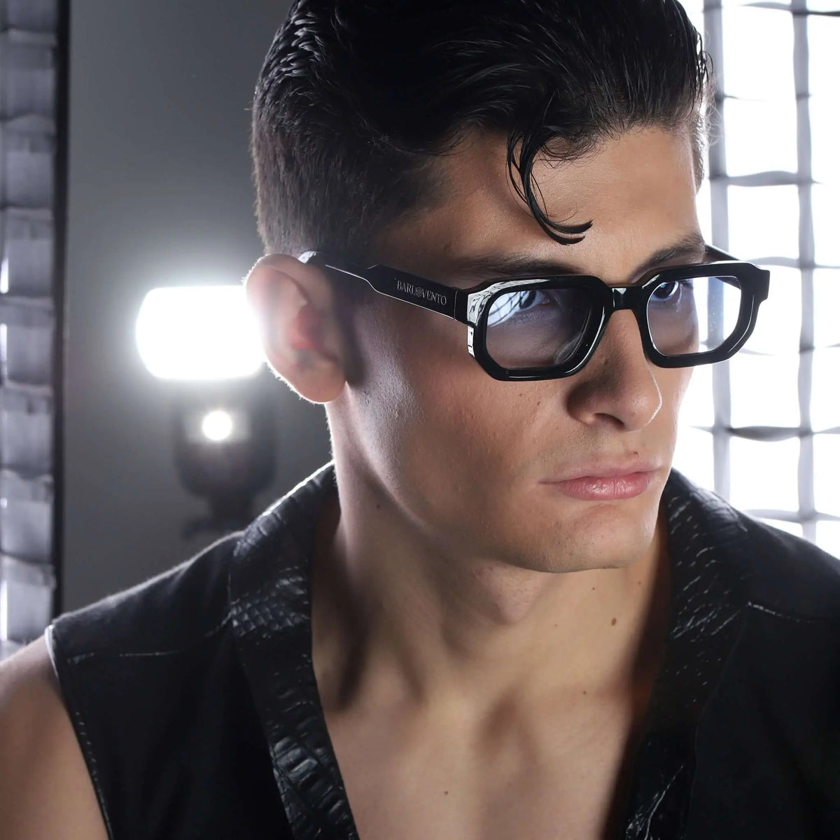 Gafas de sol con montura negra geométrica y lentes azul claro puestas en un hombre con estilo moderno.
