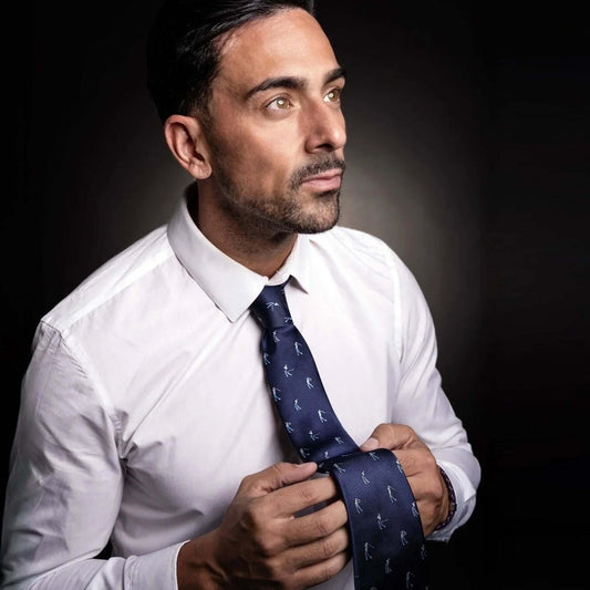 Hombre con camisa blanca y corbata azul marino de seda con estampado elegante de golfistas, estilo formal profesional.