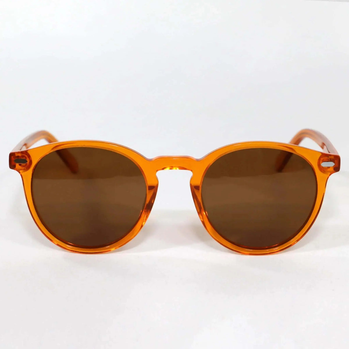 Gafas de sol redondas de acetato naranja transparente con lentes oscuras estilo vintage sobre fondo blanco.