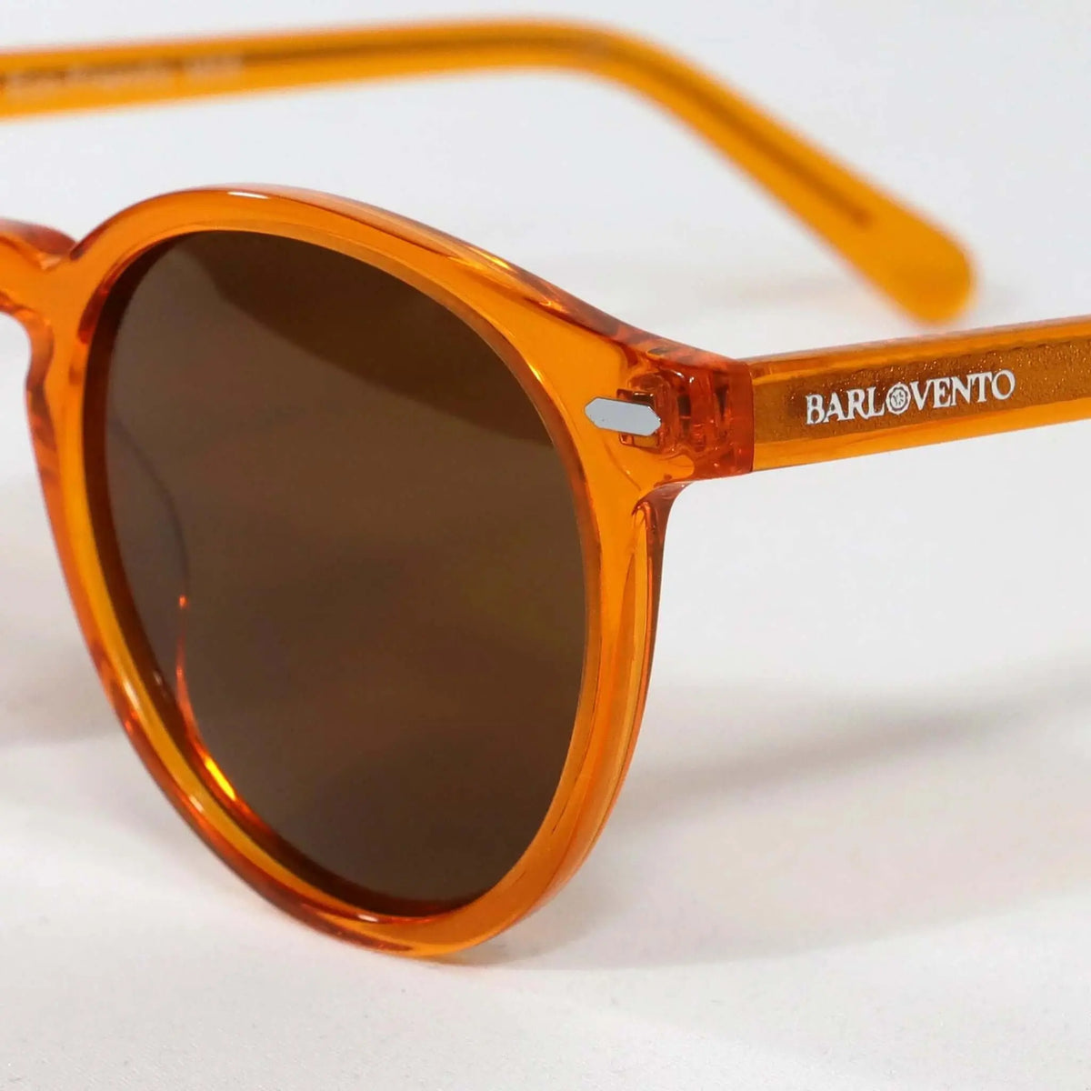 Gafas de sol redondas de acetato naranja cristal translúcido con lentes oscuras y estilo moderno y casual.